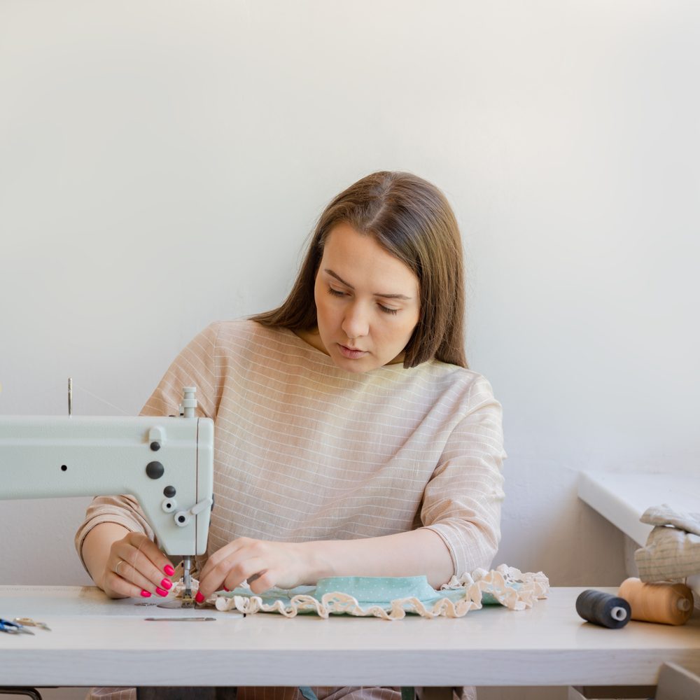Personne débutante réalisant un projet de couture simple avec une machine à coudre.