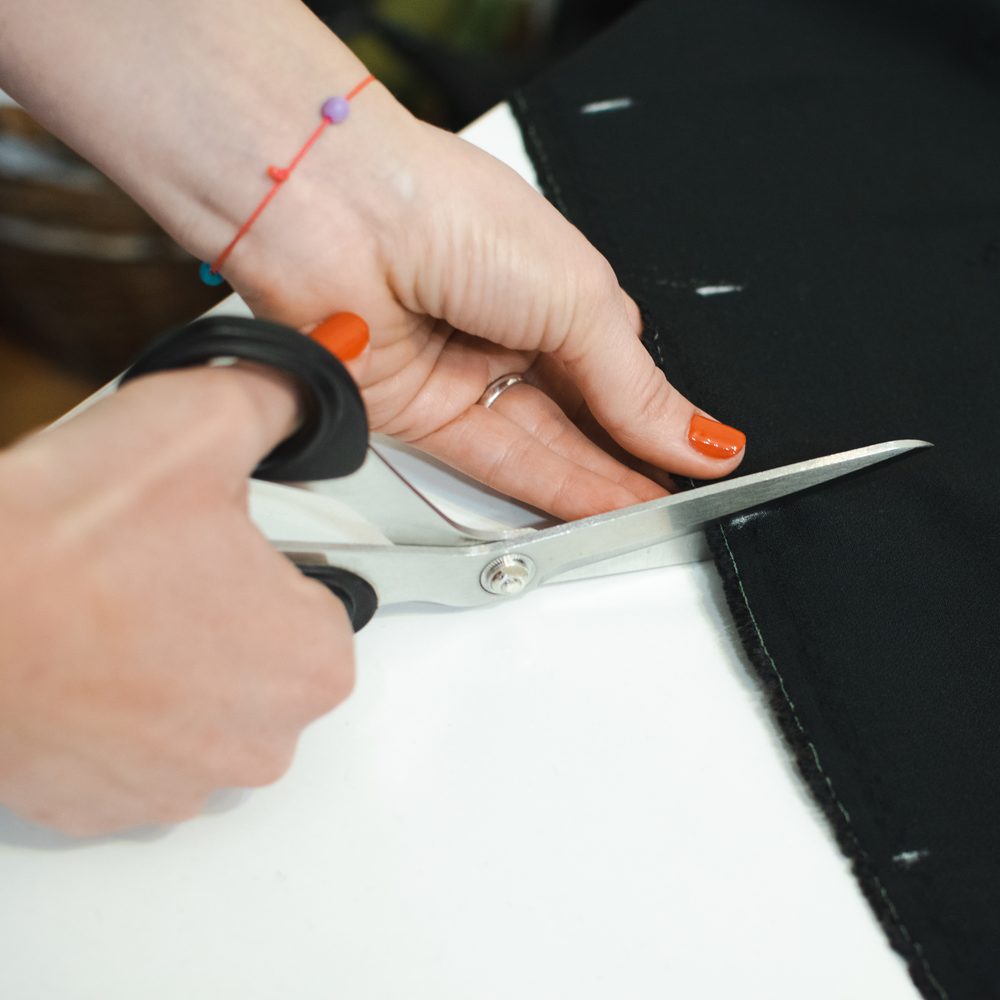 Couturière consultant des instructions de couture à côté d’une machine à coudre et de pièces de tissu.